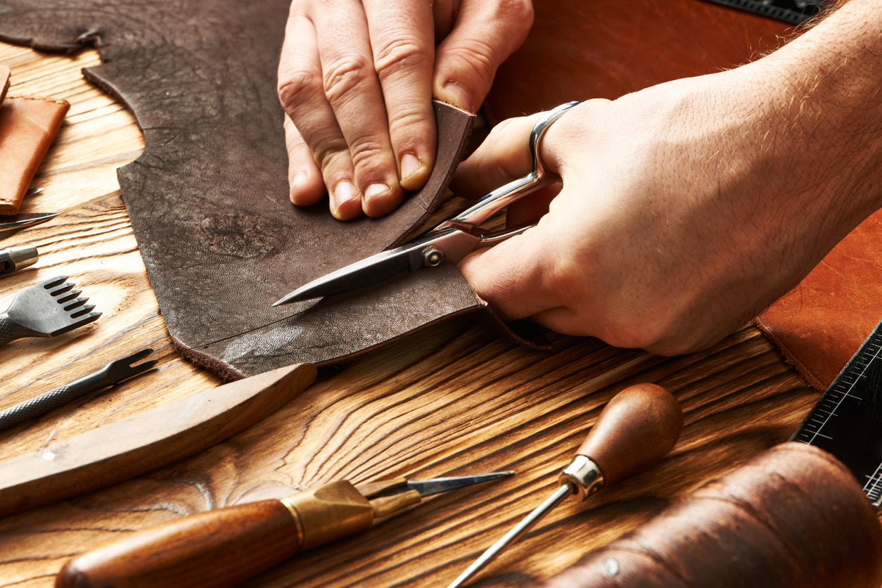 Leder wird zugeschnitten um Schuhe per Hand zu fertigen